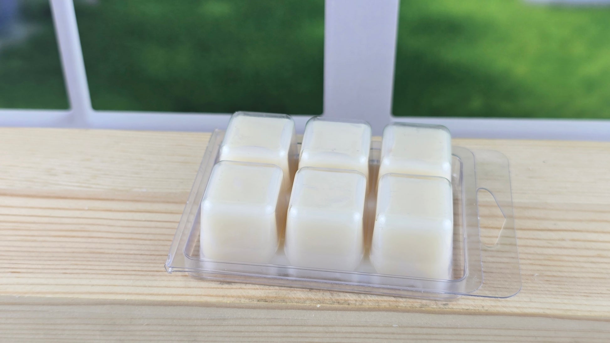 clamshell wax melt laying on wooden surface showing the back 