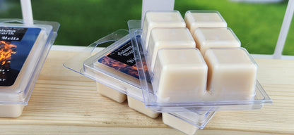 Scented wax melts in clear containers on a wooden surface with a blurred outdoor background.