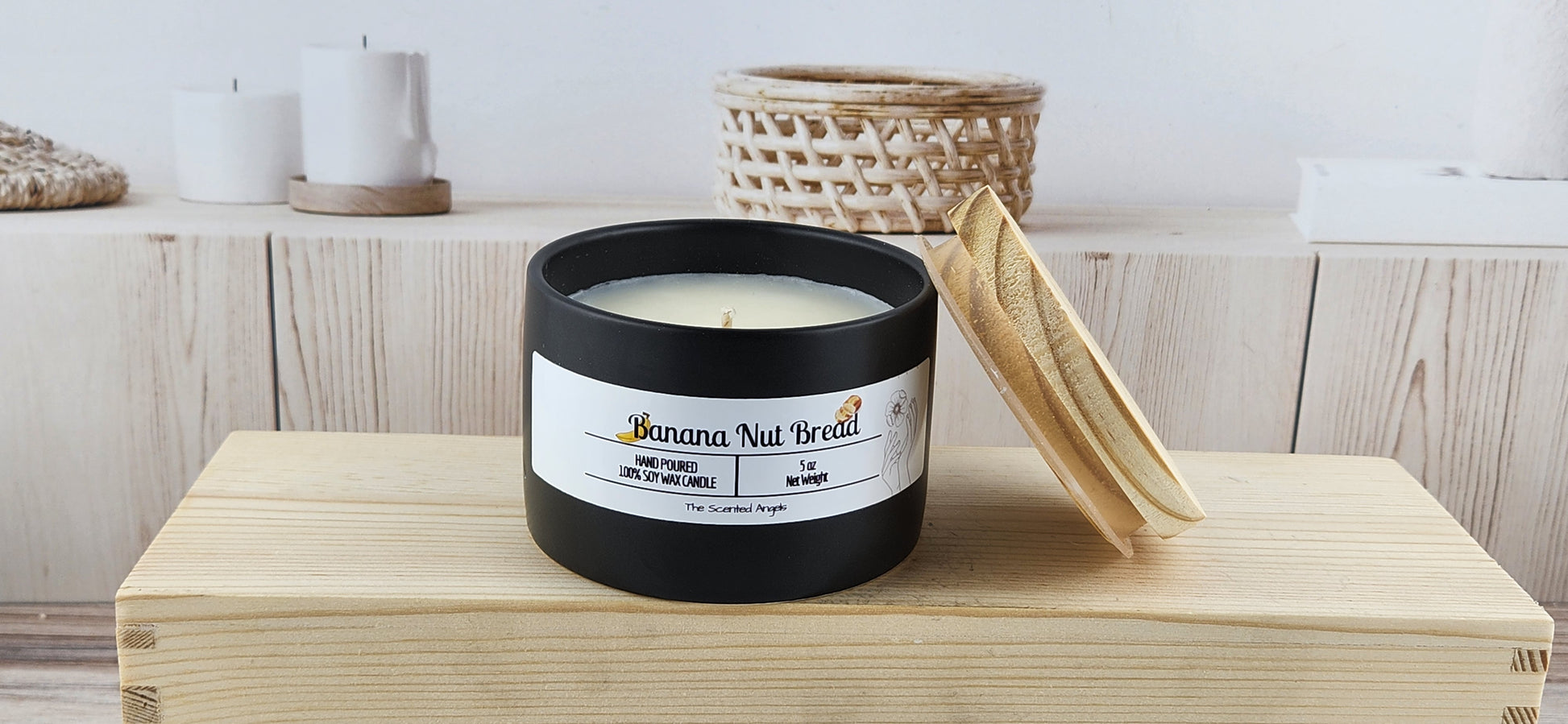 Candle labeled 'Banana Nut Bread' on a wooden block with a neutral background