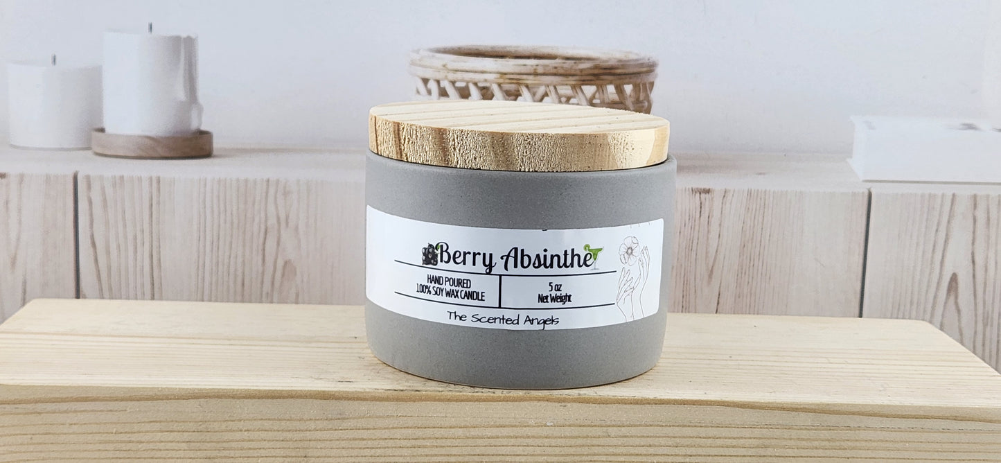 Candle labeled 'Berry Absinthe' on a wooden surface with a neutral background