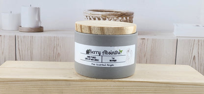 Candle labeled 'Berry Absinthe' on a wooden surface with a neutral background