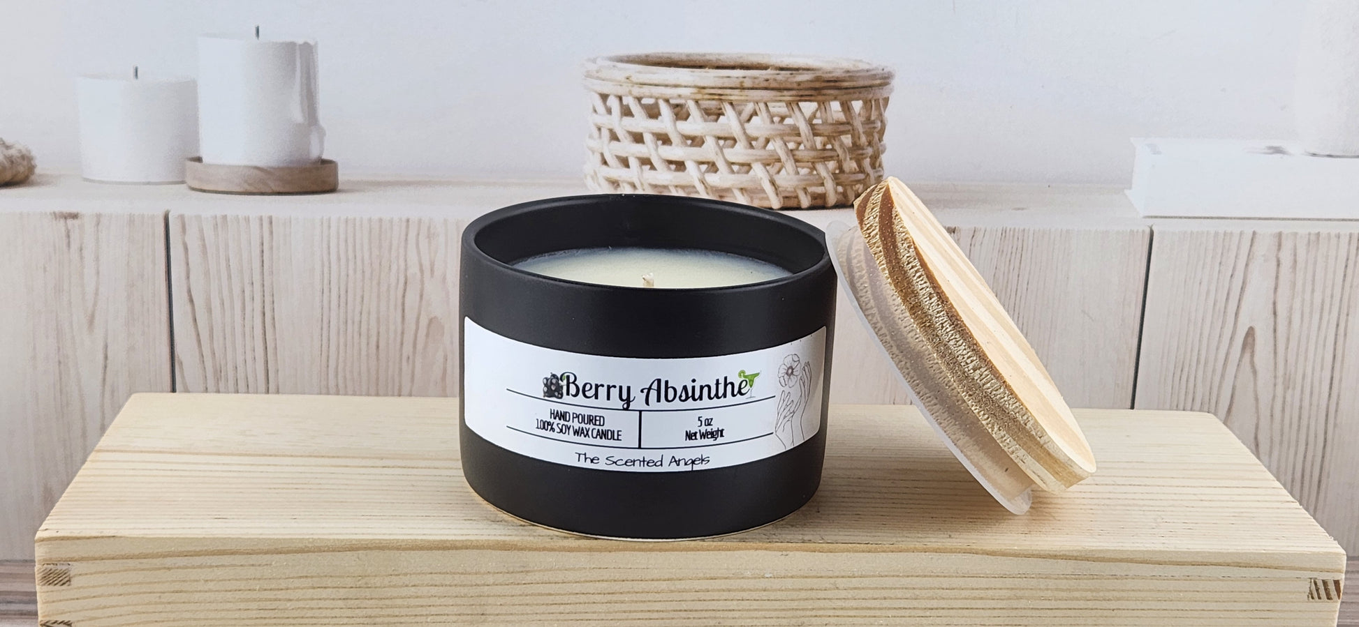 Black candle with a white label on a wooden surface, surrounded by wicker baskets and candles.