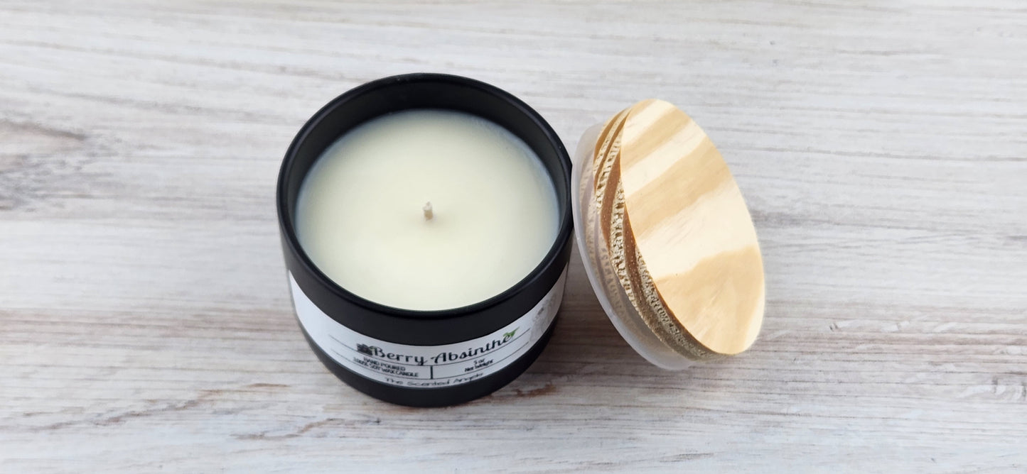 Candle in a black container with a wooden lid on a light wooden surface