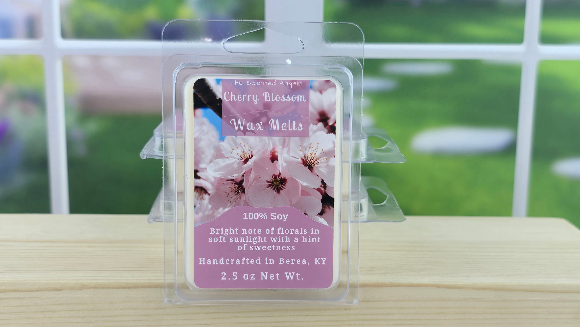 Cherry blossom wax melts packaging on a wooden surface with a blurred outdoor background