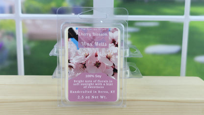 Cherry blossom wax melts packaging on a wooden surface with a blurred outdoor background