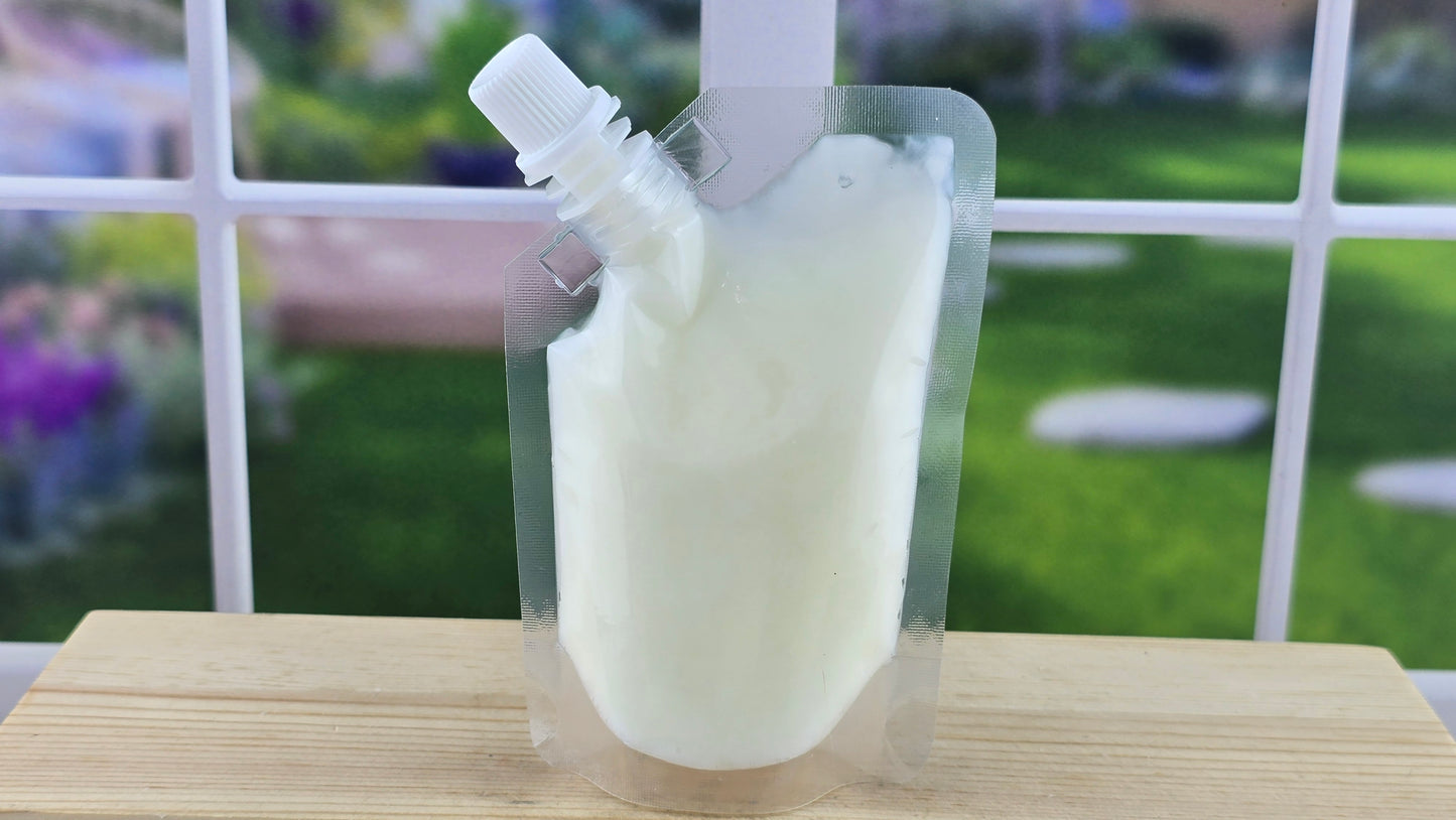 Wax melt in a transparent plastic pouch with a spout on a wooden surface.