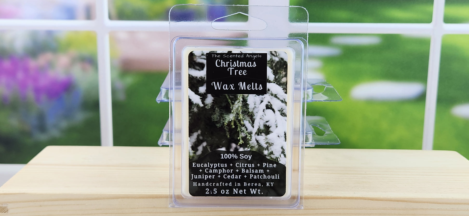Christmas Tree wax melts packaging on a wooden surface with a blurred garden background