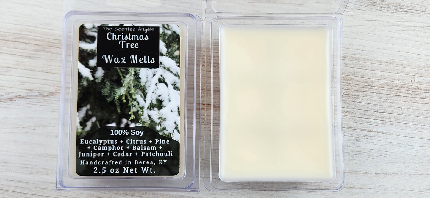 Two wax melt packages with a Christmas tree design on a wooden surface