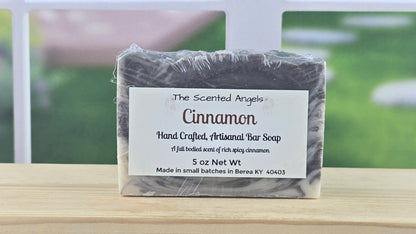 Cinnamon soap bar with a label on a wooden surface, blurred outdoor background