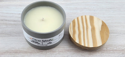 Candle in a gray container with a wooden lid on a light wooden surface