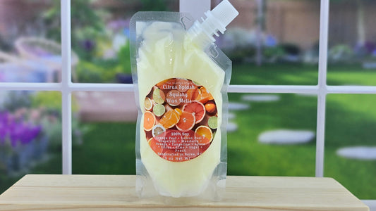 A pouch of 100% Soy Squeezy Wax Melts with a citrus splash scent, displayed on a wooden shelf with a garden and window in the background.