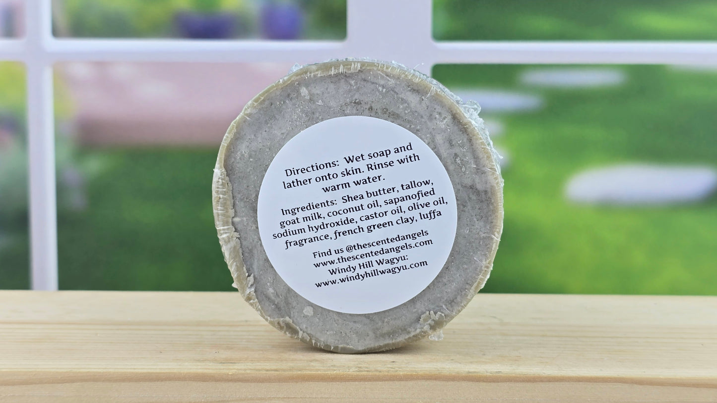 Back view of the Coastal Calm bar soap with Luffa, on a wooden surface with a blurred outdoor background.