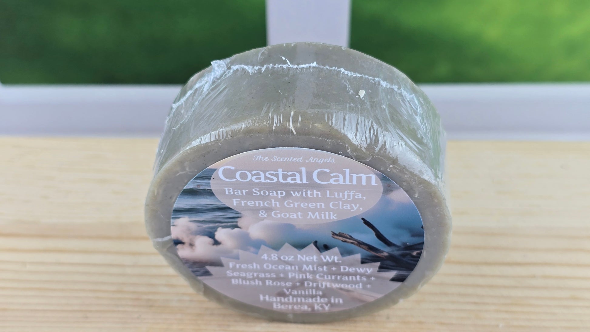 Coastal Calm bar soap on a wooden surface with a blurred outdoor background.