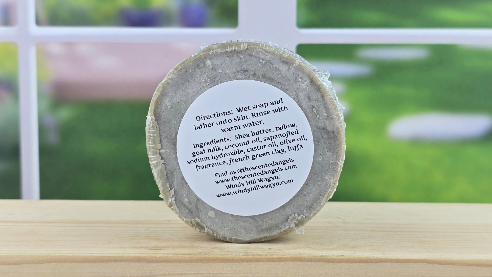 Back view of the Coastal Serenity bar soap with Luffa, on a wooden surface with a blurred outdoor background.