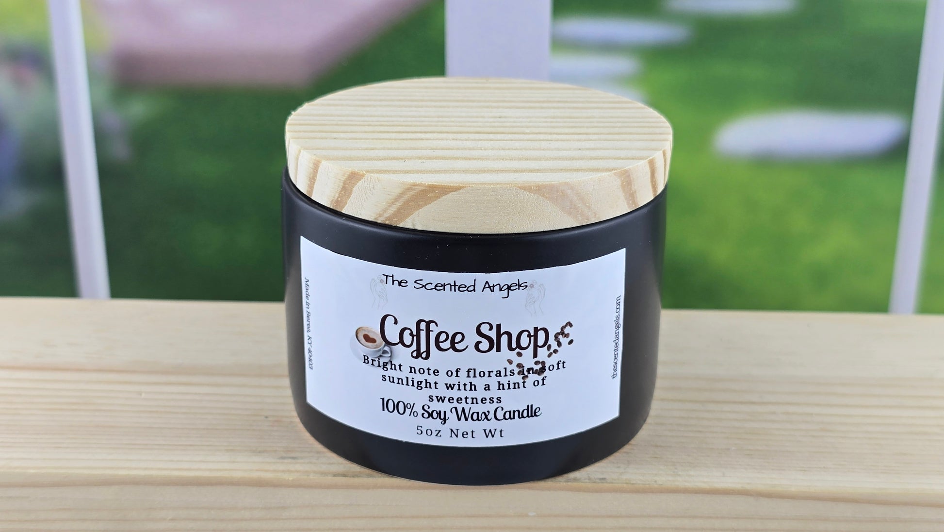 Candle labeled 'Coffee Shop' on a wooden surface with a blurred background.