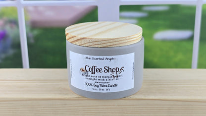 Candle in a gray container with wooden lid on a wooden surface.