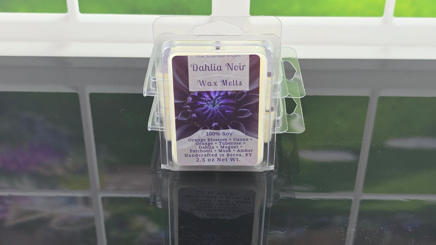Wax melt packaging labeled 'Dahlia Noir' on a reflective surface with a blurred background.