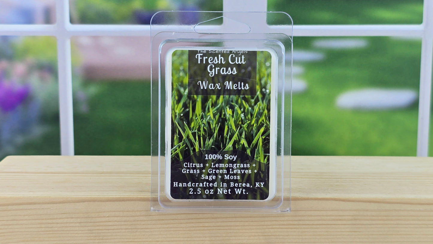 Packaged Fresh Cut Grass wax melts on a wooden surface with a garden background
