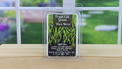 Packaged Fresh Cut Grass wax melts on a wooden surface with a garden background