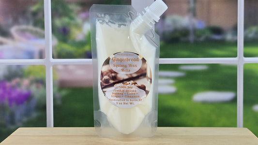 Packaged gingerbread squishy wax melts on a wooden surface with a garden background