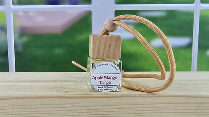 Fragrance diffuser bottle labeled 'Apple Mango Tango' with wooden top and beige rope on wooden surface.