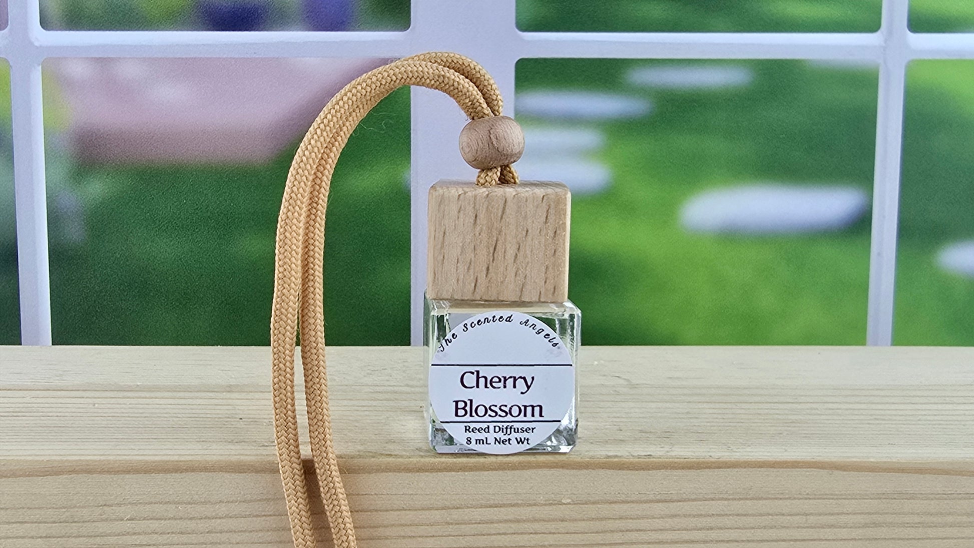 Cherry Blossom Reed Diffuser on wooden surface with blurred green background