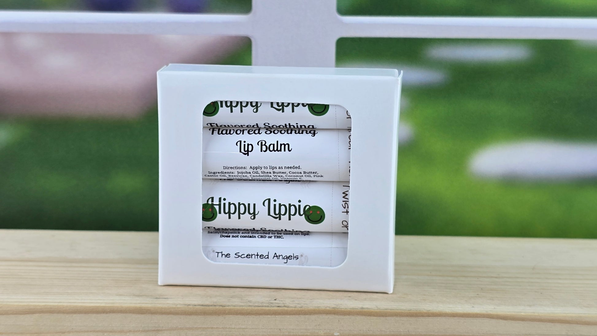 Hippy Lippie lip balm packaging on a wooden surface with a blurred outdoor background