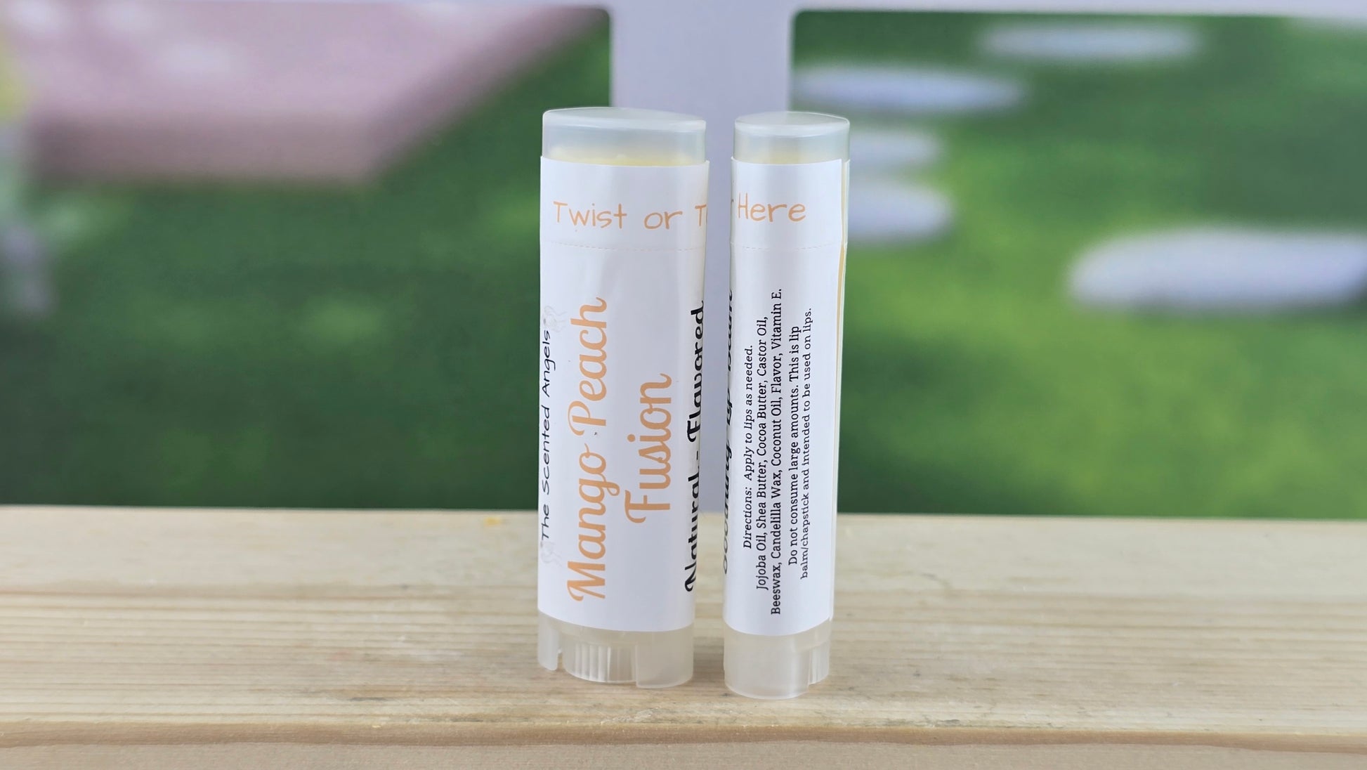 Two lip balm tubes on a wooden surface with a blurred outdoor background