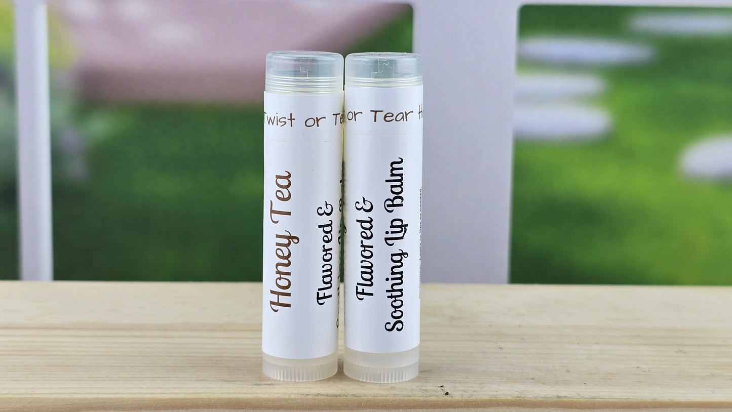 Two lip balm tubes on a wooden surface with a blurred outdoor background.