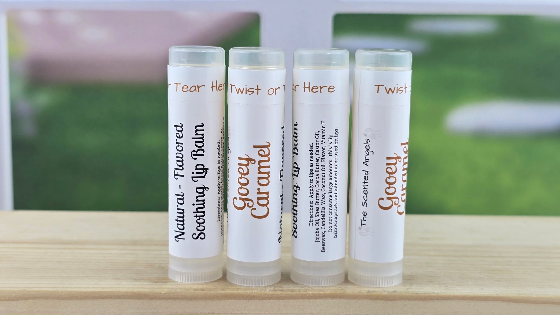 Four lip balm tubes with labels on a wooden surface