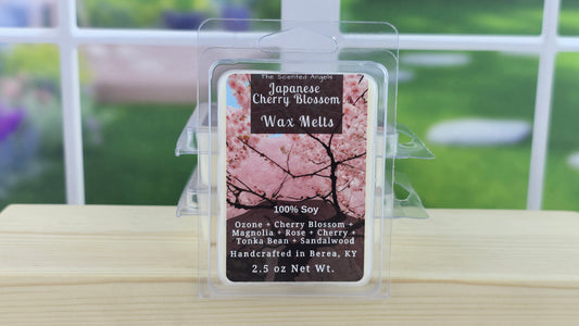 Japanese Cherry Blossom wax melt packaging on a wooden surface with a blurred outdoor background.