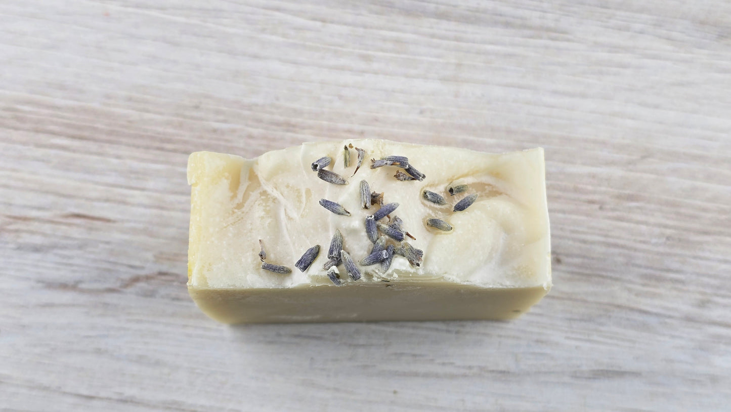 Lavender Tallow Cold Process Soap with lavender buds sitting on a wooden surface