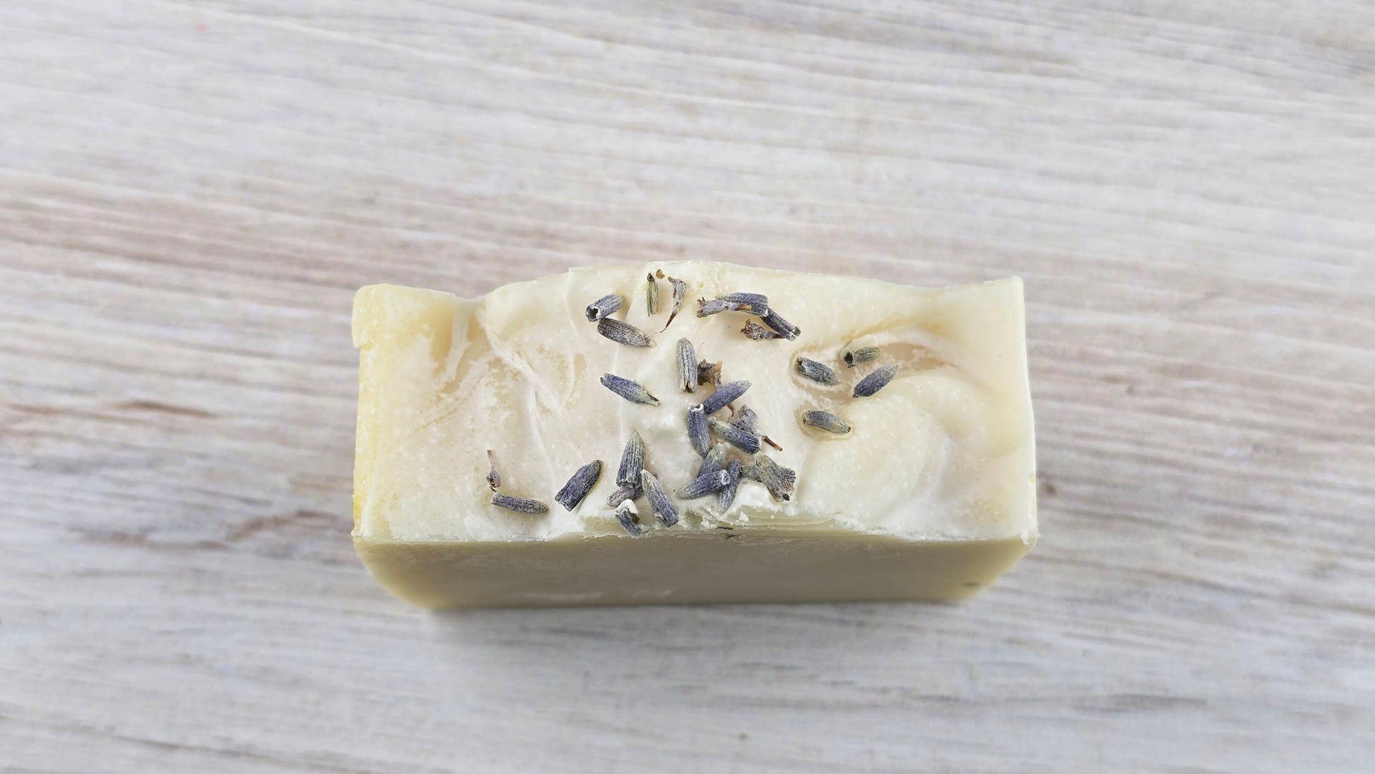 Lavender Tallow Cold Process Soap with lavender buds sitting on a wooden surface
