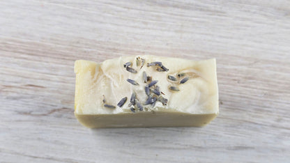 Lavender Tallow Cold Process Soap with lavender buds sitting on a wooden surface