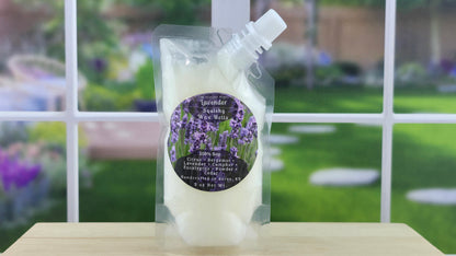 A squeezy wax melt package with a clear label that reads 'Lavender' and has an image of lavender flowers, placed on a wooden surface with a grassy background.