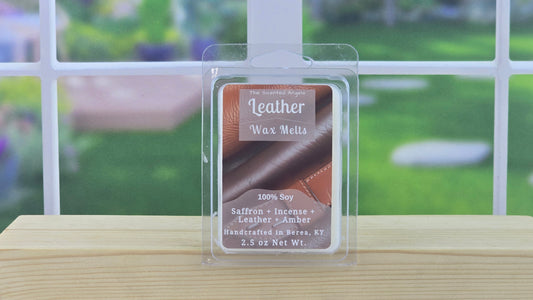 Packaged leather wax melts on a wooden surface with a blurred outdoor background