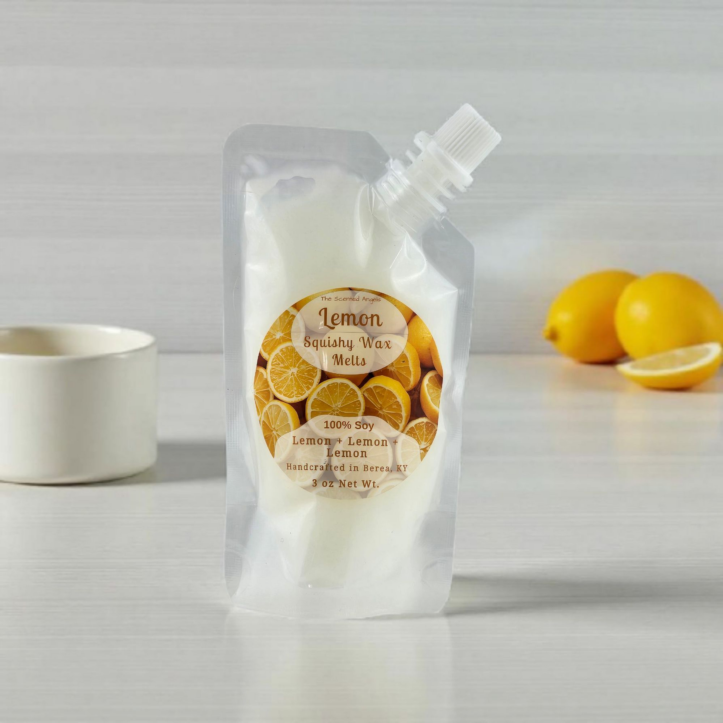 Packaging of lemon-scented wax melts on a white surface with lemons in the background.