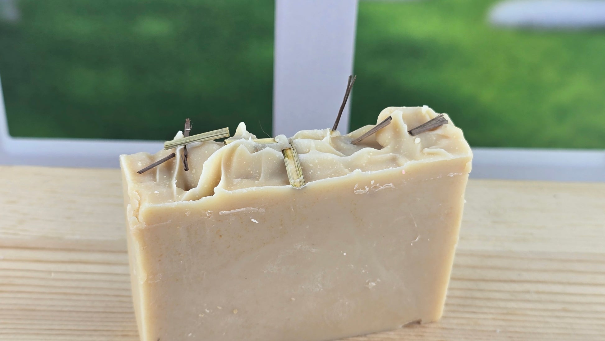 Bar of soap with visible herbs on a wooden surface