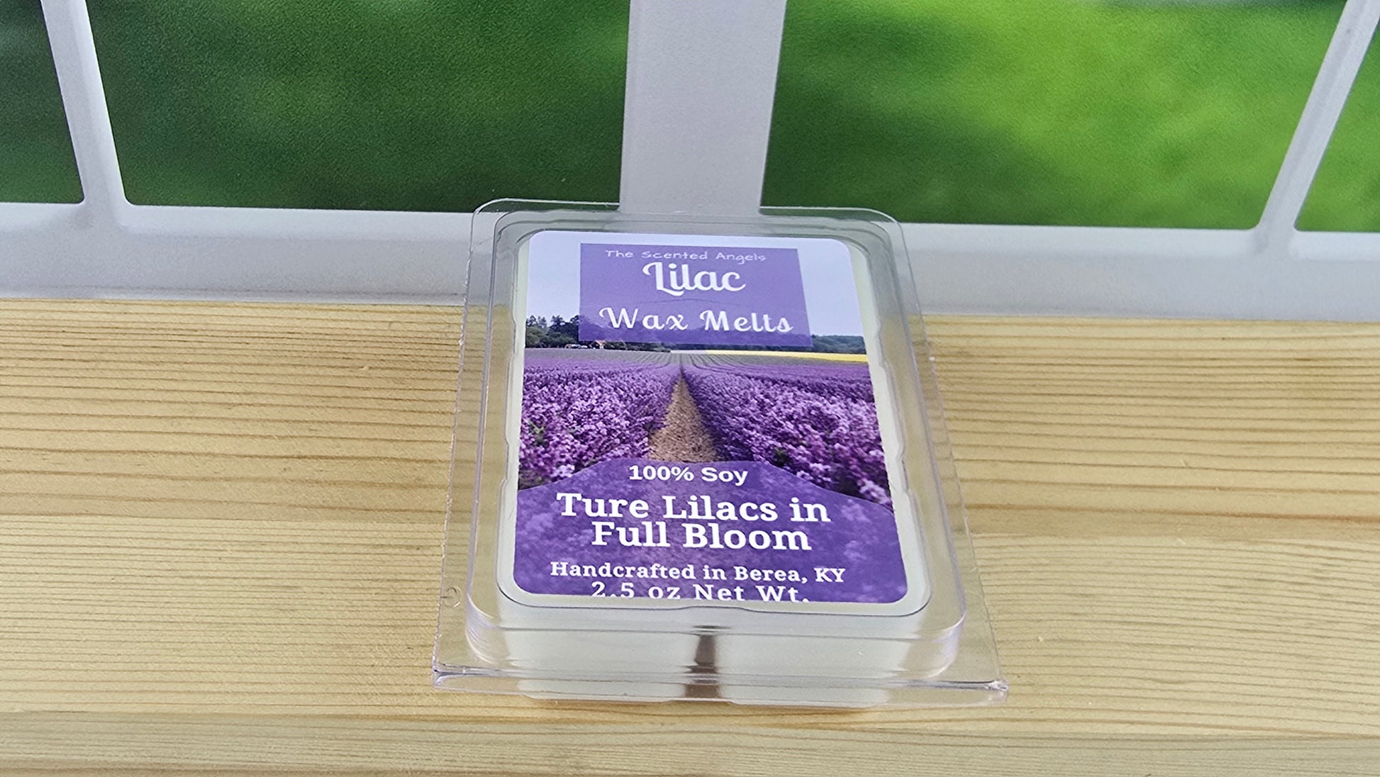 Lilac wax melt package on a wooden surface with a window in the background