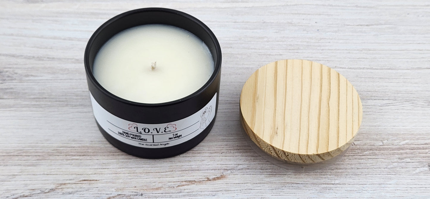 Candle in a black container with a wooden lid on a light wooden surface