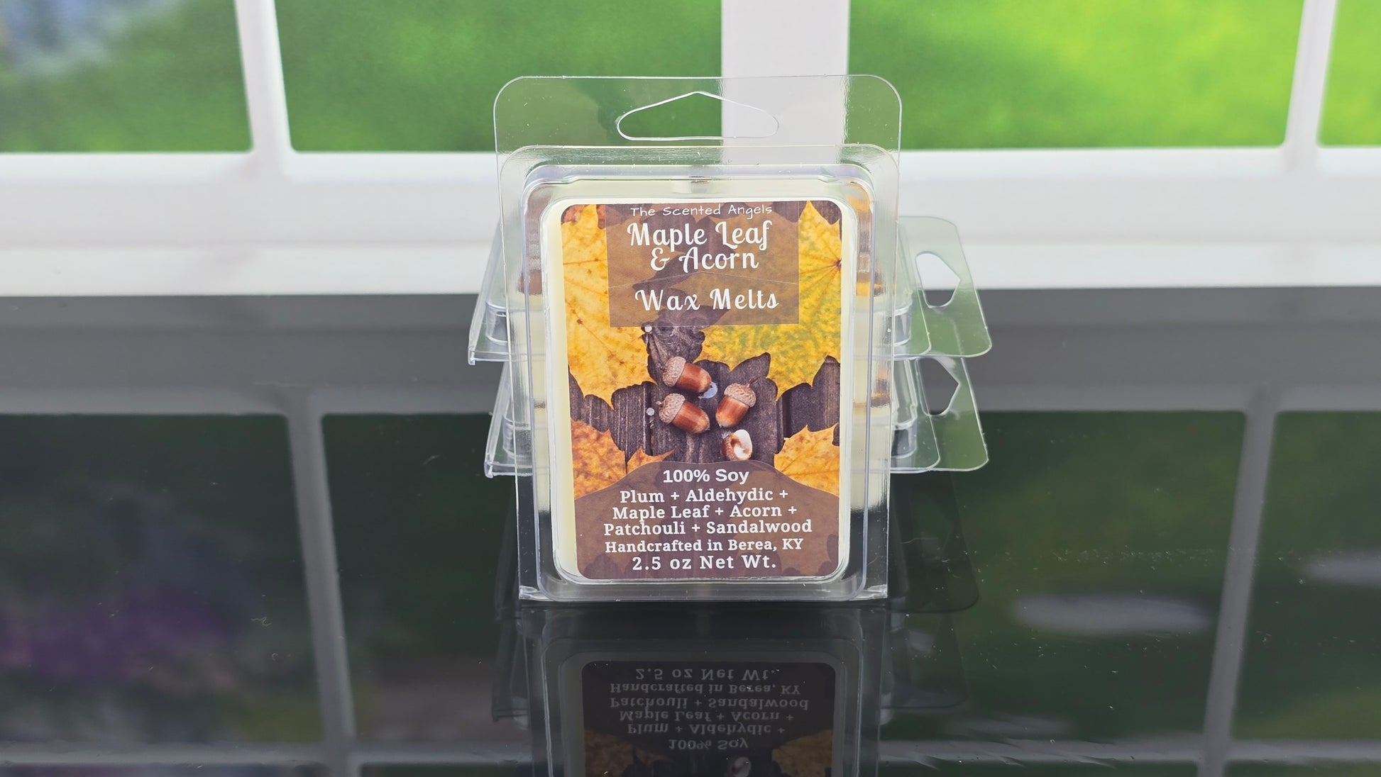 Packaged wax melts with a maple leaf and acorn design on a window sill.