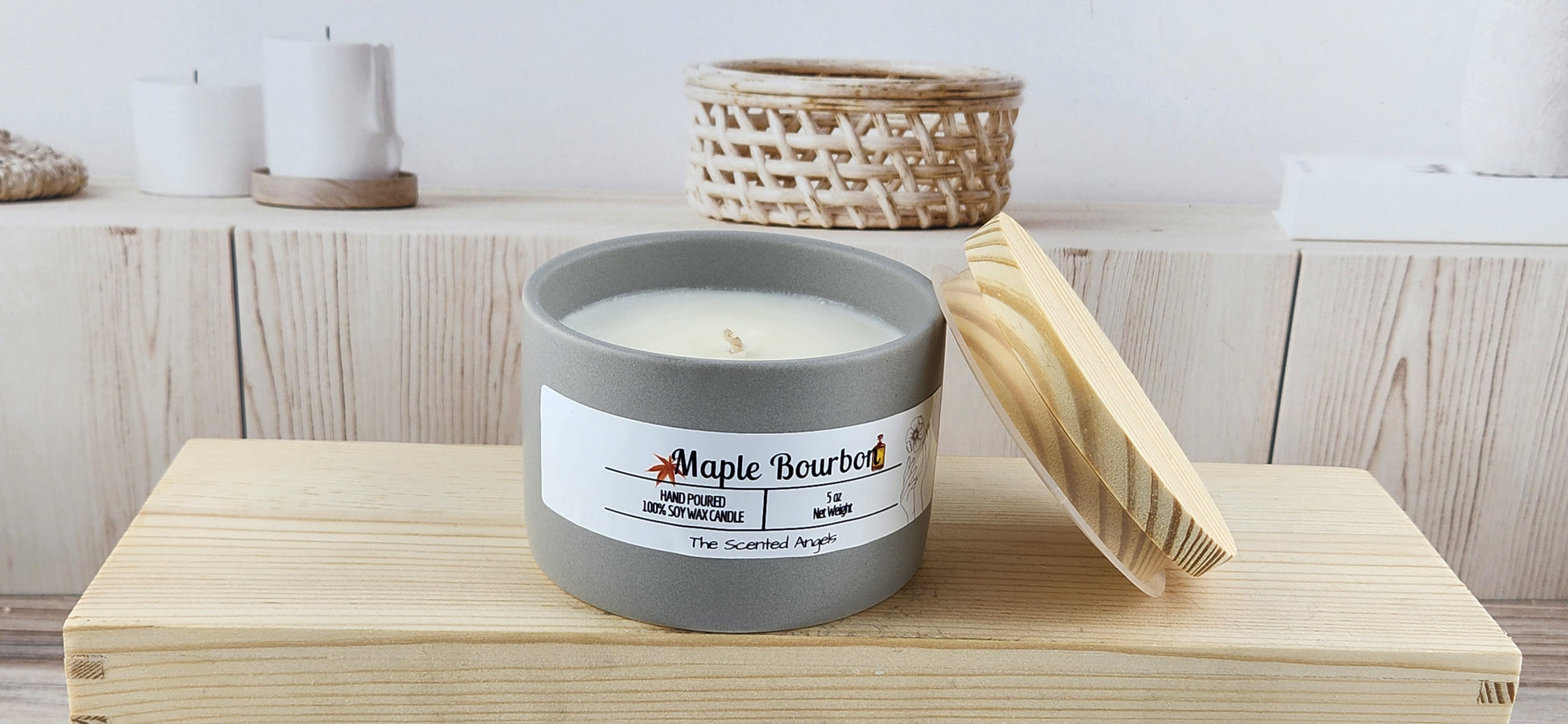Candle labeled 'Maple Bourbon' on a wooden surface with a blurred background
