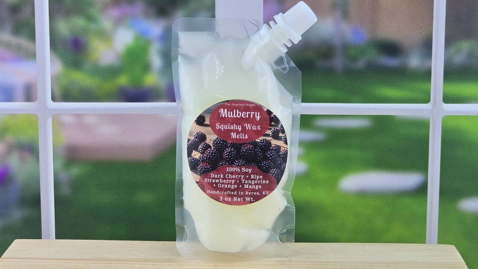 Packaged wax melt with Mulberry on a wooden surface with a garden background