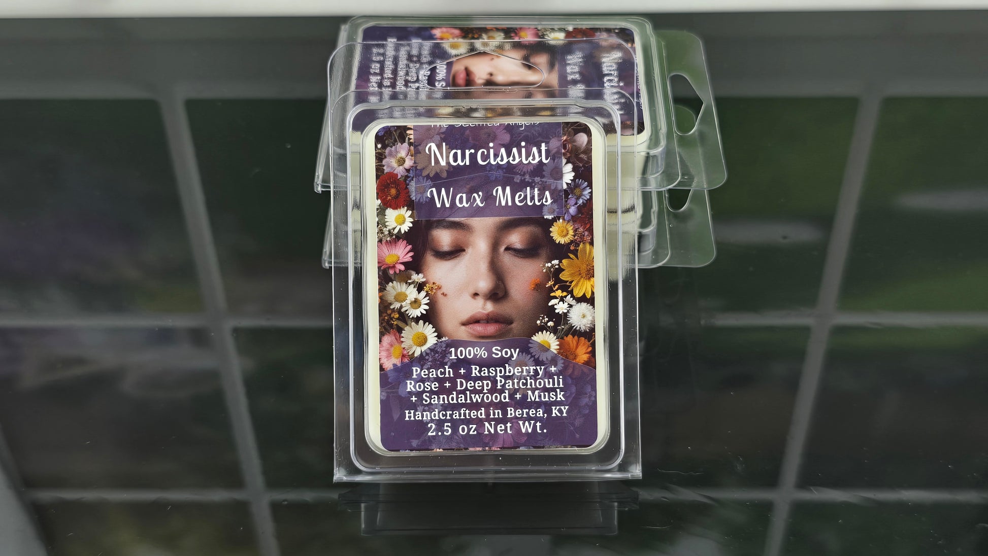 Stack of wax melt packages with decorative labels on a tiled surface