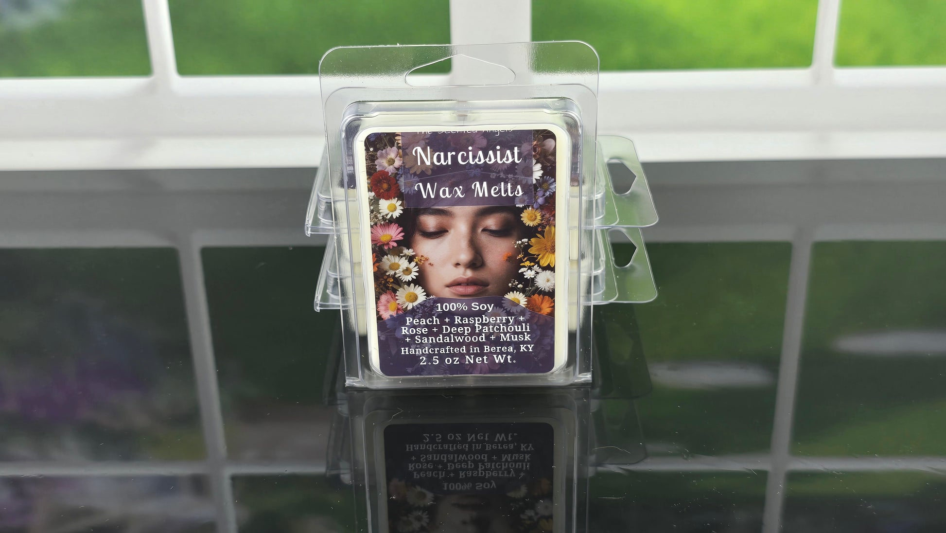 Wax melt packaging with a woman's face on a clear stand against a tiled wall background.