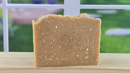 Bar of brown soap on a wooden surface, blurred green background