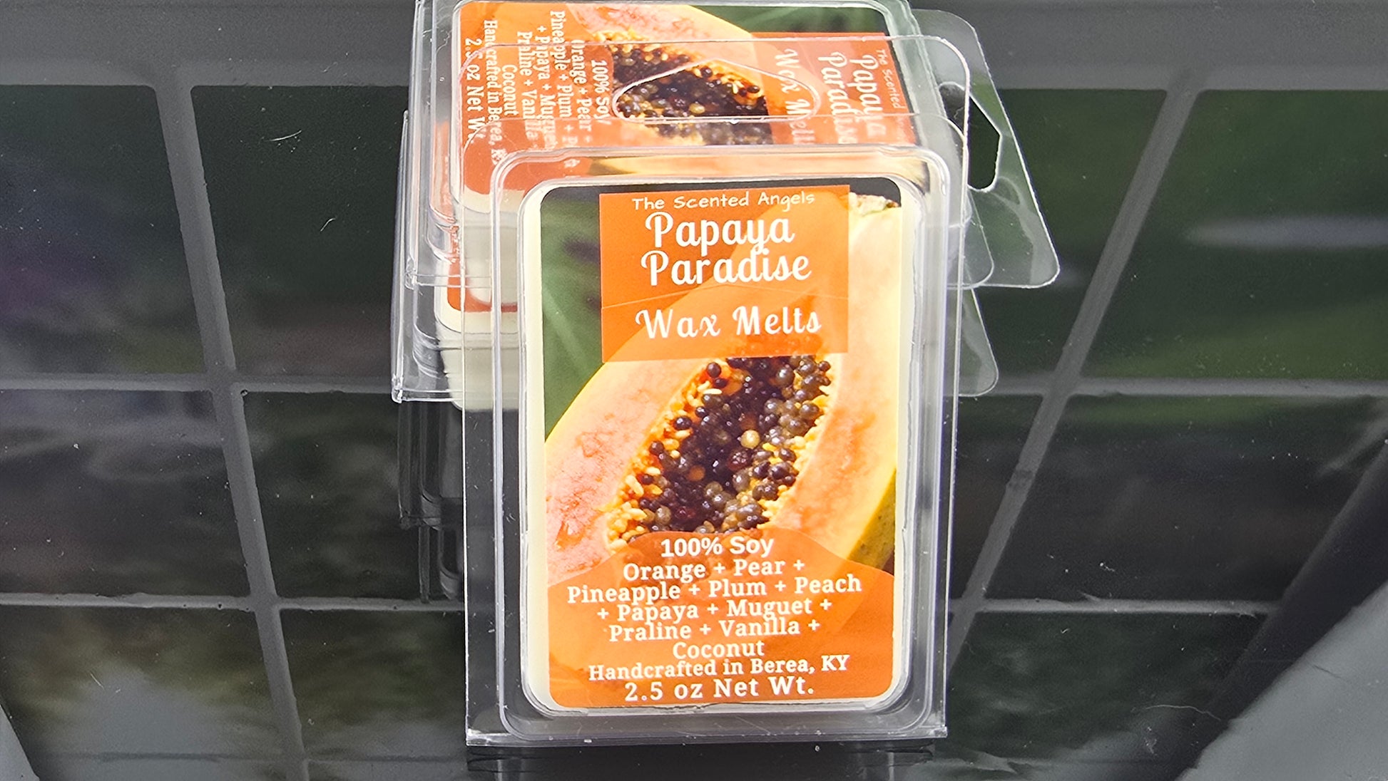 Packaged papaya wax melts on a reflective surface