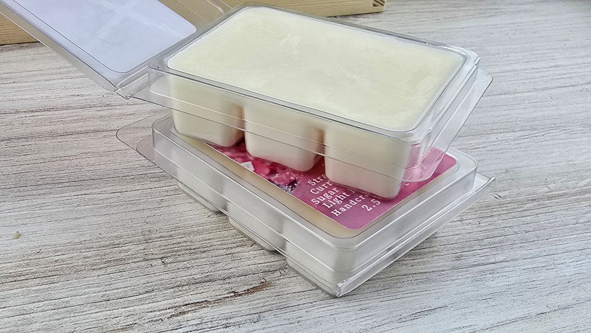 Packaged wax melts with a pink label on a wooden surface