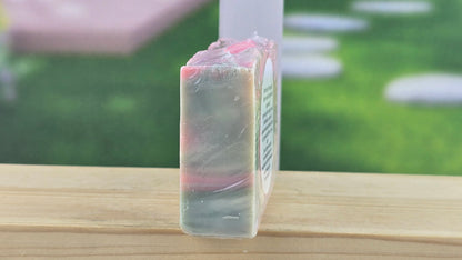 Bar of soap on a wooden surface with a blurred outdoor background