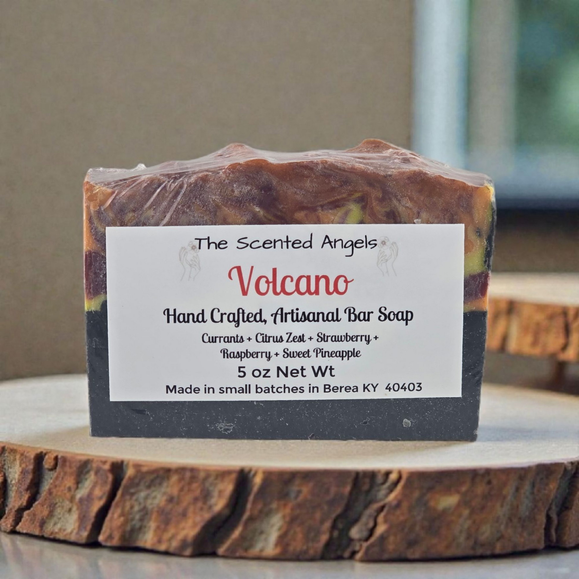 Handcrafted artisanal bar soap labeled 'Volcano' by The Scented Angels on a wooden surface.